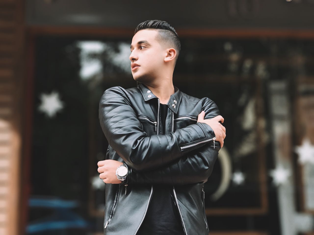 Services-02 A young man in a leather jacket stands outdoors, embodying modern urban fashion.